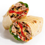 Two grilled wraps cut open to show steak, red peppers, greens, and melted cheese, wrapped in a lightly toasted tortilla on a light gray background.